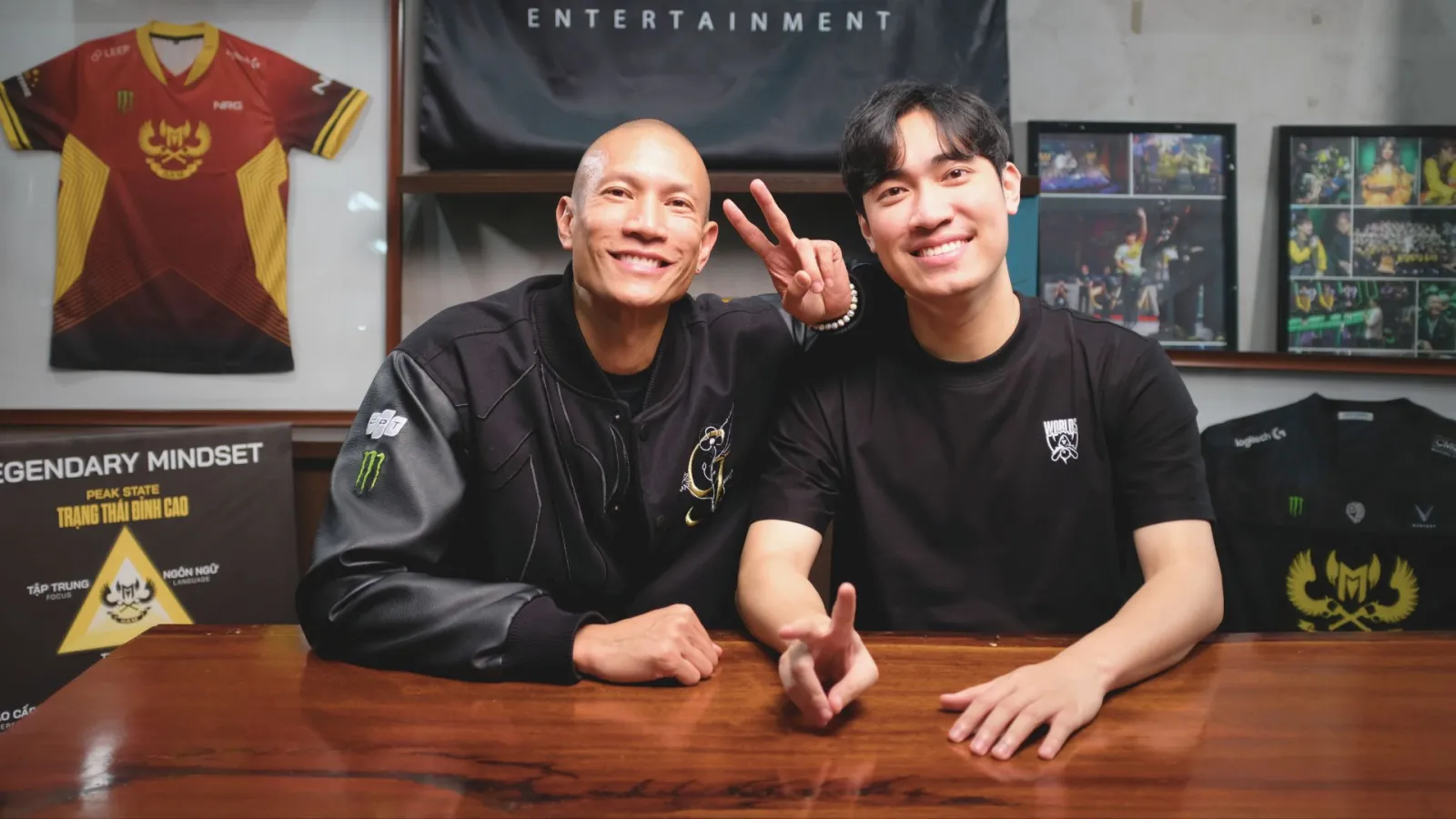 TK Nguyen with a guest at the GĀM Changers desk, GAM jerseys on the wall behind them