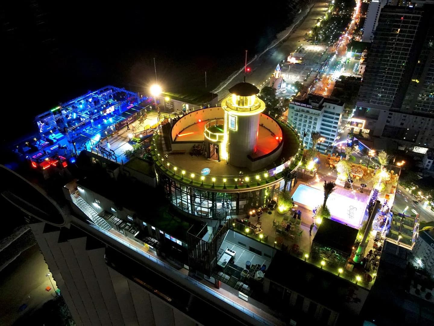 Skylight’s lighthouse deck from above at night, the beach club lit blue and Tran Phu below