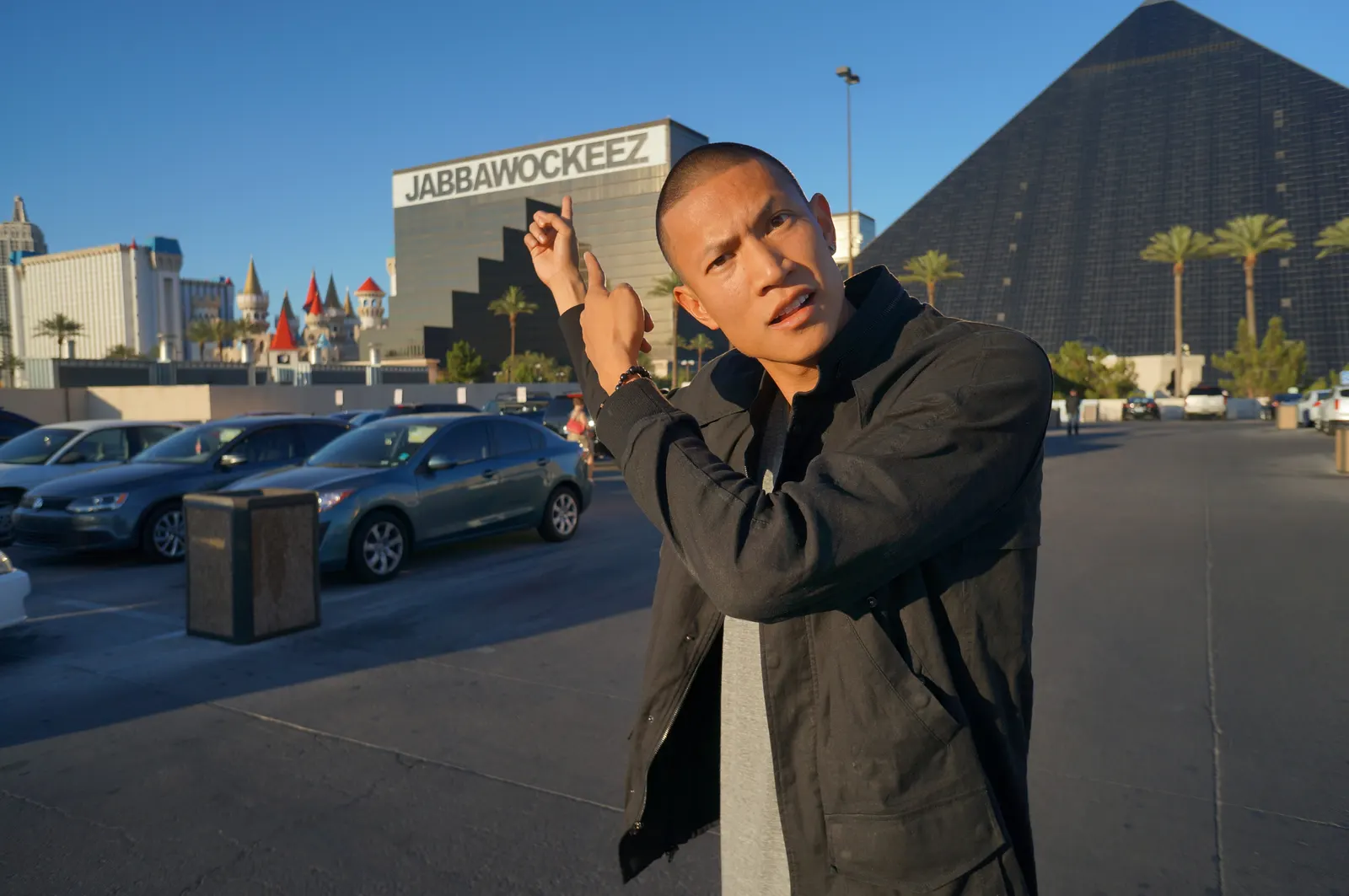 TK Nguyen pointing up at the JABBAWOCKEEZ sign on the Luxor, Las Vegas, beside the pyramid